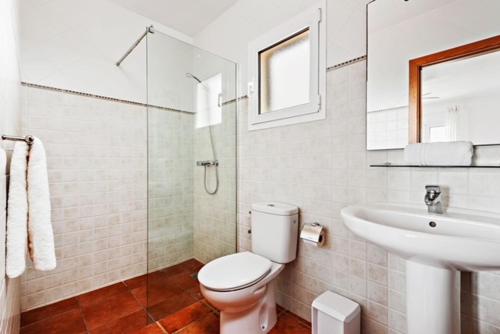 een witte badkamer met een toilet en een wastafel bij Villa etxe txekia in Cala Galdana