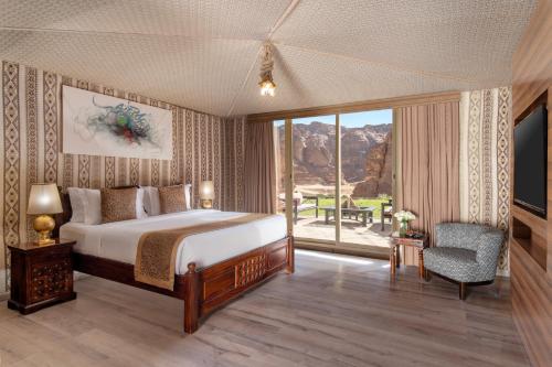 a bedroom with a bed and a large window at Shaden Resort in AlUla