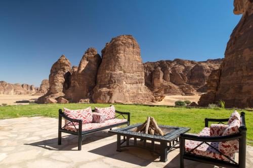a patio with two benches and a table and some rocks at Shaden Resort in AlUla