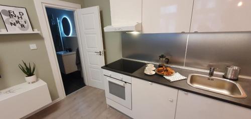 una cocina con armarios blancos y fregadero en CS14 Gold Apartment, en Budapest