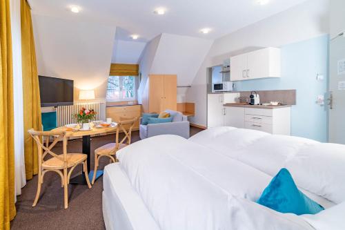 une chambre avec deux lits, une table et une cuisine dans l'établissement Apartment Hotel Schreier, à Lindau