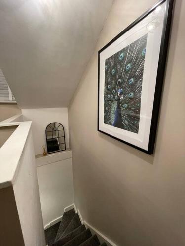 a staircase with a picture of a peacock painting on the wall at Stylish 3 Bed Home in Clitheroe in Clitheroe