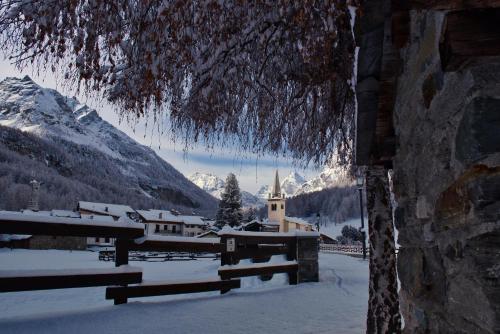 un villaggio ricoperto di neve con una chiesa in montagna di Case Gran Paradiso Rhemes Notre Dame a Rhêmes-Notre-Dame