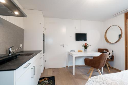 a white kitchen with a white table and a sink at Chalet Ruestel in Amden