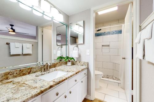 a bathroom with a sink and a toilet and a mirror at Mystic Harbor #104 in Padre Island