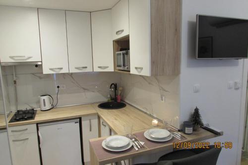 una pequeña cocina con armarios blancos y microondas en Studio apartman Oboj Maksimir en Zagreb