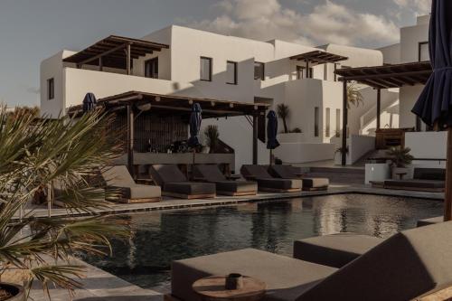 un complexe avec une piscine, des chaises et un bâtiment dans l'établissement Casa Cook Mykonos - Adults Only, à Ornos