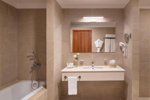 a bathroom with a sink and a tub and a mirror at Shaden Resort in AlUla