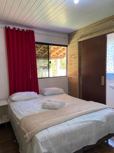 1 dormitorio con 1 cama grande y cortina roja en Pousada da Heloisa, en Imbituba