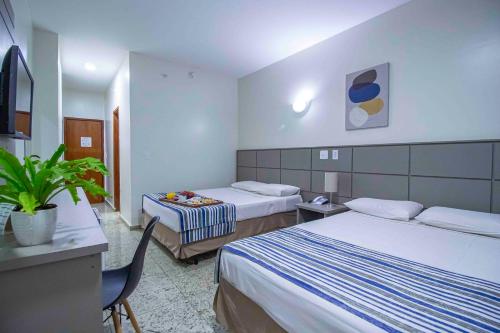 a hotel room with two beds and a table at Hotel Vilage Inn Ribeirão Preto & Convenções in Ribeirão Preto