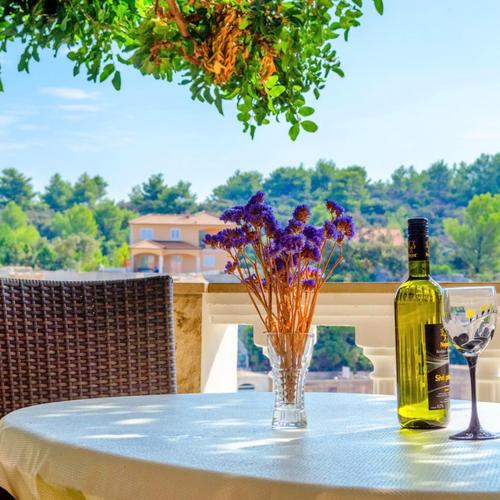 a bottle of wine and a vase of flowers on a table at Apartments Katica's Place in Prizba