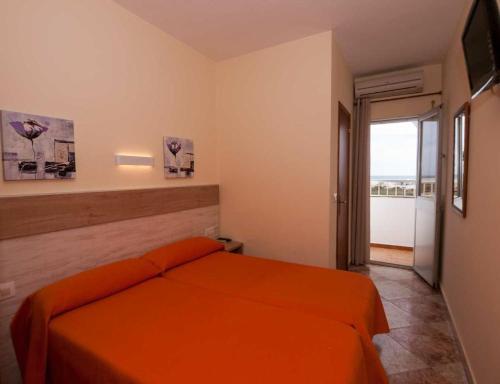 1 dormitorio con cama de color naranja y balcón en Hostal Sonrisa del Mar, en Conil de la Frontera