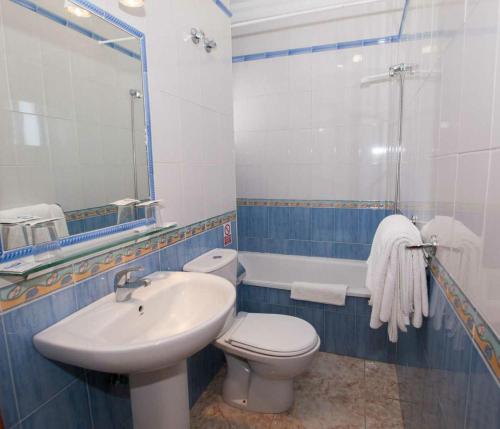 a bathroom with a sink and a toilet and a mirror at Hostal Sonrisa del Mar in Conil de la Frontera