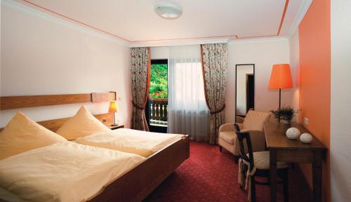 ロフにあるMoselhotel & Restaurant Zur Traube GmbHのベッド、デスク、窓が備わるホテルルームです。