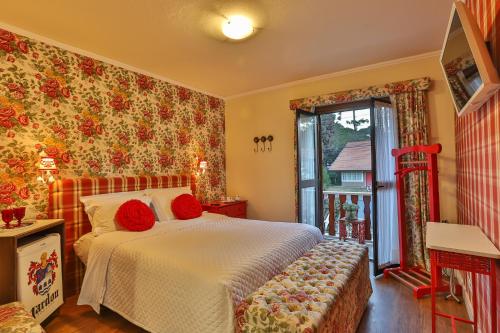 Un dormitorio con una cama con almohadas rojas y una ventana en Pousada Jardon, en Campos do Jordão