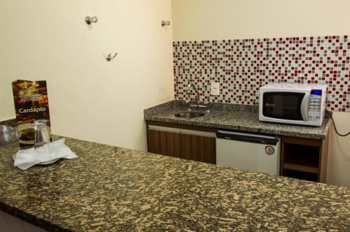 a kitchen with a counter top with a microwave on it at LEON PARK HOTEL e CONVENÇÕES - Melhor Custo Benefício in Campinas