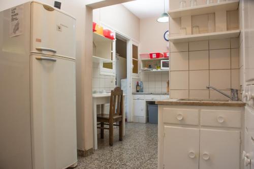 a white kitchen with a refrigerator and a table at Alamo Hostel & Suites in Mendoza