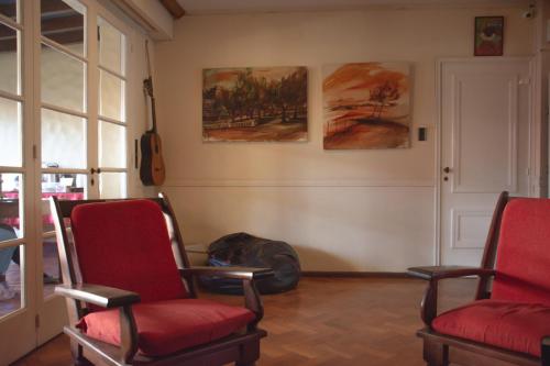 a room with red chairs and paintings on the wall at Alamo Hostel & Suites in Mendoza