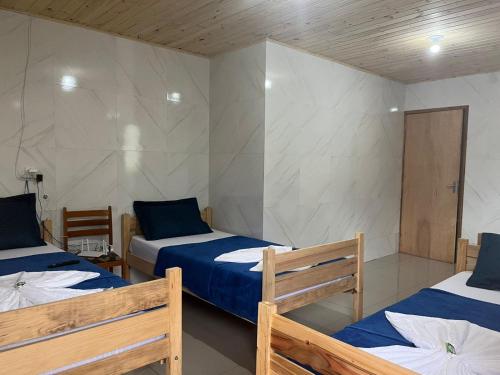 a room with two beds with blue sheets at Edicula Fundos in Jordãozinho