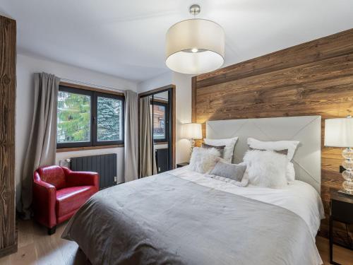 une chambre avec un grand lit et une chaise rouge dans l'établissement Appartement Rénové, 3 Chambres, Balcon ensoleillé, Proche Centre et Remontées Mécaniques à Megève - FR-1-569-26, à Megève