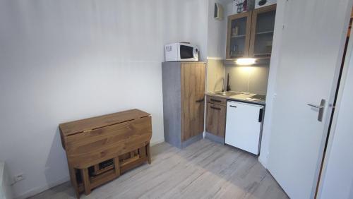 a small kitchen with a white refrigerator and a table at La Foux d'Allos - Studio 4 pers. in Allos