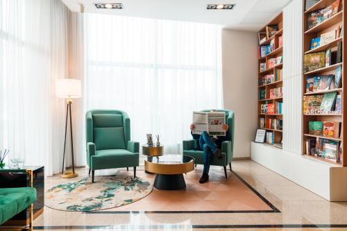 a living room with two green chairs and a table at Arche Hotel Puławska Residence in Warsaw