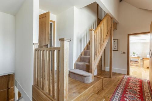 uma escada de madeira numa casa com um tapete em The Old Library em Painswick