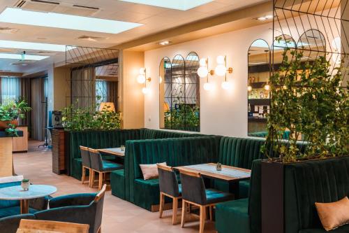 a restaurant with green booths and tables and plants at Arche Hotel Puławska Residence Warszawa in Warsaw