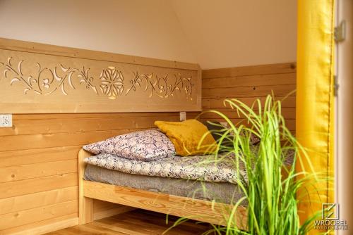 a small bed in a wooden room with a plant at Domek u Justyny in Kościelisko