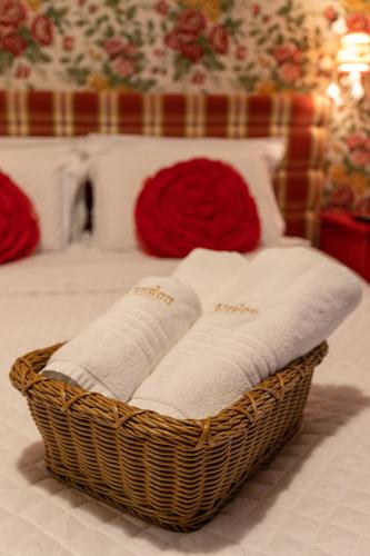 a basket filled with white towels on a bed at Pousada Jardon Campos do Jordão - Exclusiva para Adultos in Campos do Jordão