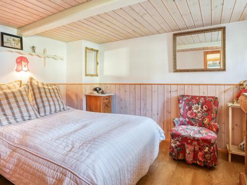 a bedroom with a bed and a chair and a mirror at Holiday home Læsø LIII in Læsø