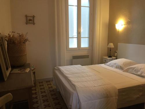 - une chambre avec un grand lit blanc et une fenêtre dans l'établissement Maison au bord de mer, à Saintes-Maries-de-la-Mer