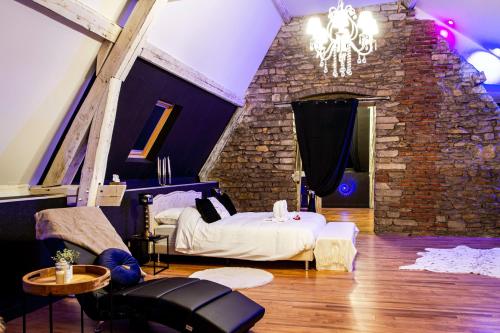 een slaapkamer met een bed en een bakstenen muur bij Royal Room - Love-room proche de Nancy in Liverdun