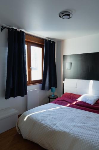 une chambre avec un grand lit et une fenêtre dans l'établissement KASA JURA - Au coeur des monts, à Saint-Claude