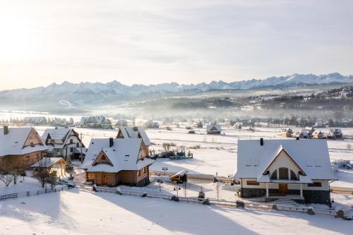 a village covered in snow with mountains in the background at Boska Osada in Czarna Góra