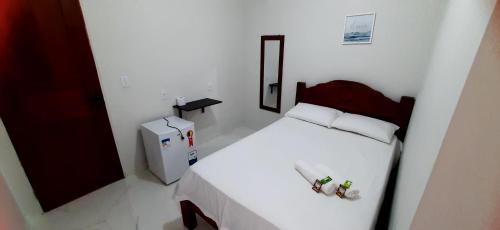 Habitación blanca pequeña con cama y nevera en Pousada Brilho dos Lençóis, en Barreirinhas