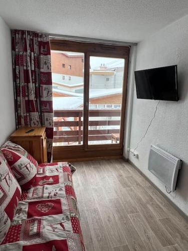 une chambre avec un lit et une grande fenêtre dans l'établissement Altineige Center village, à Val Thorens