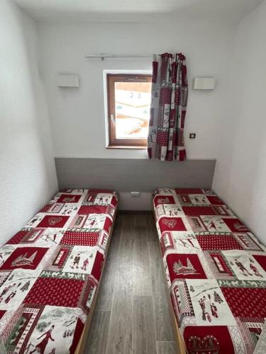deux lits dans une petite pièce avec une fenêtre dans l'établissement Altineige Center village, à Val Thorens