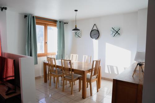 een eetkamer met een houten tafel en stoelen bij KASA JURA - Au coeur des monts in Saint-Claude