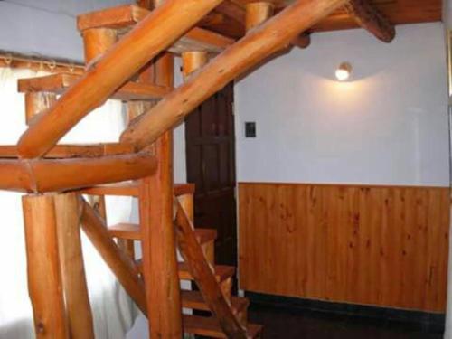 una escalera de caracol de madera en una habitación con una pared blanca en Excelente casa en alquiler en villa cura Brochero. en Villa Cura Brochero