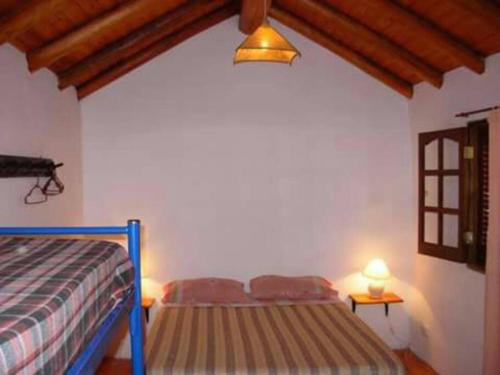 1 dormitorio con 2 camas, lámpara y ventana en Excelente casa en alquiler en villa cura Brochero. en Villa Cura Brochero