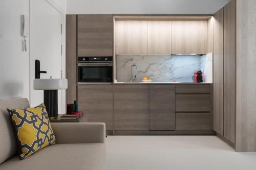 cocina con armarios de madera y sofá en Apartamentos Las Torres, en Madrid