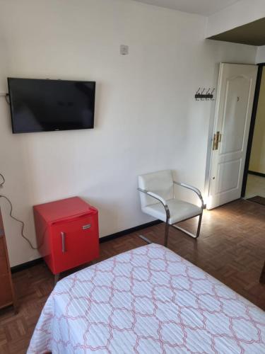 Habitación con cama, silla y TV de pantalla plana. en GORRITI VIEW en Lomas de Zamora