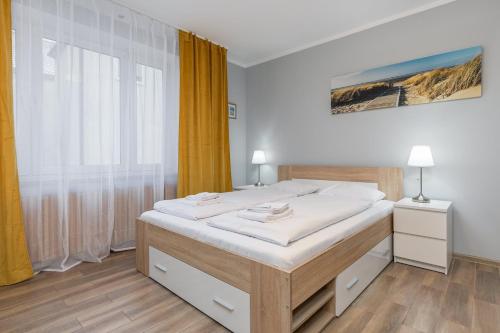 a bedroom with a bed with white sheets and a window at Apartamenty przy Promenadzie by Renters in Świnoujście