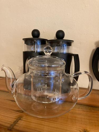 szklany dzbanek do herbaty siedzący na stole z dzbankiem do kawy w obiekcie KARUSA’s Farm Cottage w mieście Oudtshoorn