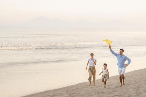 a family running on the beach with a kite at InterContinental Bali Resort, an IHG Hotel in Jimbaran