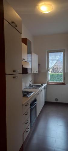 eine Küche mit weißen Schränken und einem Fenster in der Unterkunft Presolana Home in Castione della Presolana