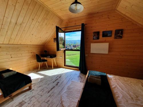 a bedroom with a large window in a wooden cabin at Młynówka Domek przy Młynie in Krościenko