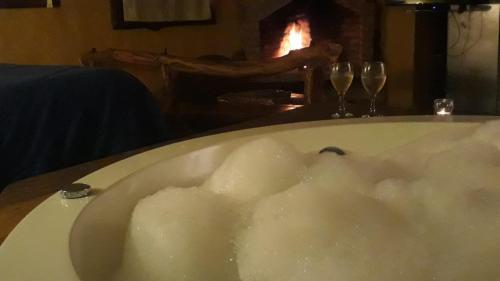a bath tub filled with foam next to two wine glasses at Del Viejo Camino in El Bolsón