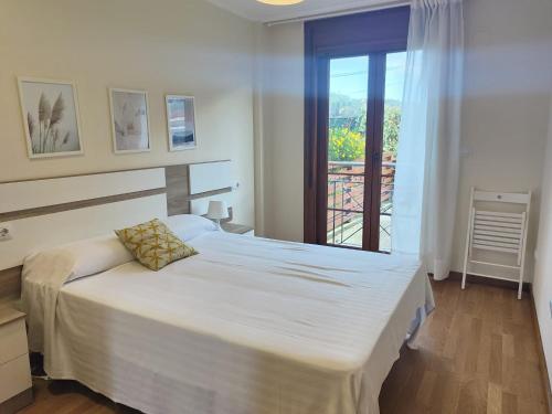- une chambre avec un grand lit blanc et une fenêtre dans l'établissement Apartagal-Mar de Vicedo, à O Vicedo